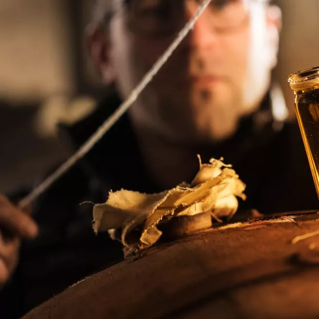 Image of a person pulling a vial of cognac from a barrel.